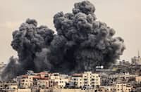 A plume of smoke rises in the sky of Gaza City during an Israeli airstrike on October 9, 2023. Israel relentlessly pounded the Gaza Strip overnight and into October 9 as fighting with Hamas continued around the Gaza Strip, as the death toll from the war against the Palestinian militants surged above 1,100. (Photo by MAHMUD HAMS / AFP)