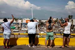 Residents attempt to find mobile phone signal in the aftermath of hurricane Otis in Acapulco, Guerrero State, Mexico, on 27 October 2023. Airlines began to evacuate tourists from Mexico's beachside city of Acapulco on Friday after a scale-topping Category 5 hurricane left a trail of destruction and at least 27 people dead, authorities said on 27 October 2023. (Photo by RODRIGO OROPEZA / AFP)
