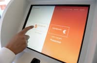 FILE PHOTO: A person touches the screen of a bitcoin ATM of Bitchain. (Photo by Josep LAGO / AFP)
