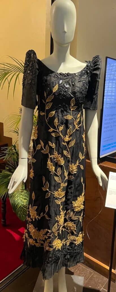 A black terno of dyed piña fabric embellished with intricate beading and leaf applique in gold and black.