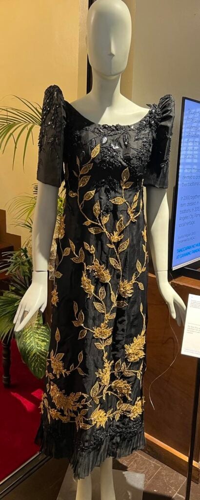 A black terno of dyed piña fabric embellished with intricate beading and leaf applique in gold and black.