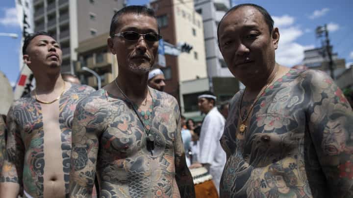 FILE PHOTO: Participants pose to show their traditional Japanese tattoos (Irezumi), related to the Yakuza, during the annual Sanja Matsuri festival in the Asakusa district of Tokyo on 20 May 2018. (Photo by Behrouz MEHRI / AFP)