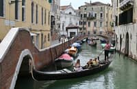 FILE PHOTO: A view taken on 31July 2023 shows tourists taking a Gondola ride across a canal in Venice. UNESCO is recommending that Venice be placed on the list of World Heritage in Danger, as "insufficient" measures have been taken to fight the deterioration of the site due in particular to mass tourism and climate change. (Photo by ANDREA PATTARO / AFP)