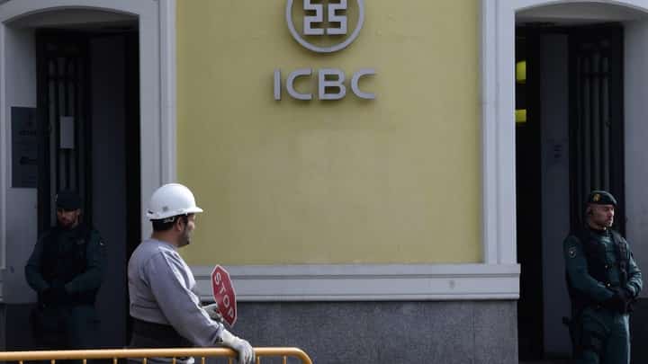 Spanish Guardia Civil and a workman stand outside the Madrid branch of China's biggest lender ICBC after its director and a deputy director were arrested as part of a probe into the suspected laundering of at least 40 million euros ($44.5 million) in Madrid on February 17, 2016. (Photo by JAVIER SORIANO / AFP)