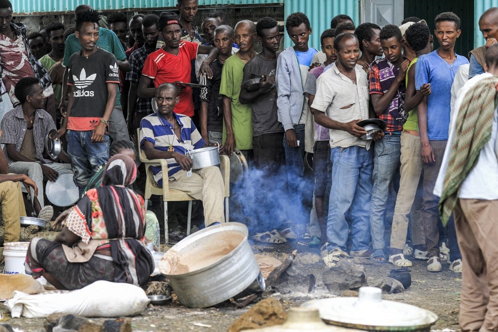 FILE PHOTO: Ethiopian refugees of the Qemant ethnic group queue for food at a camp in the village of Basinga. (Photo by ASHRAF SHAZLY / AFP)
