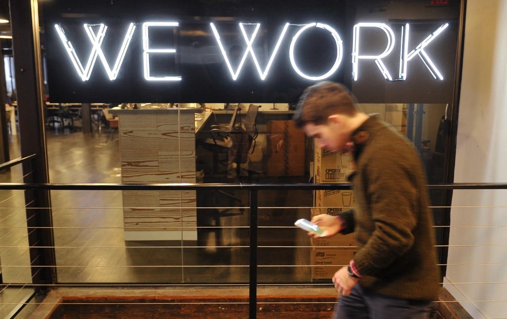 FILE: "A man walks past the neon sign in front of the "We Work" co-operative co-working space on 13 March 2013 in Washington, DC. AFP PHOTO/Mandel NGAN