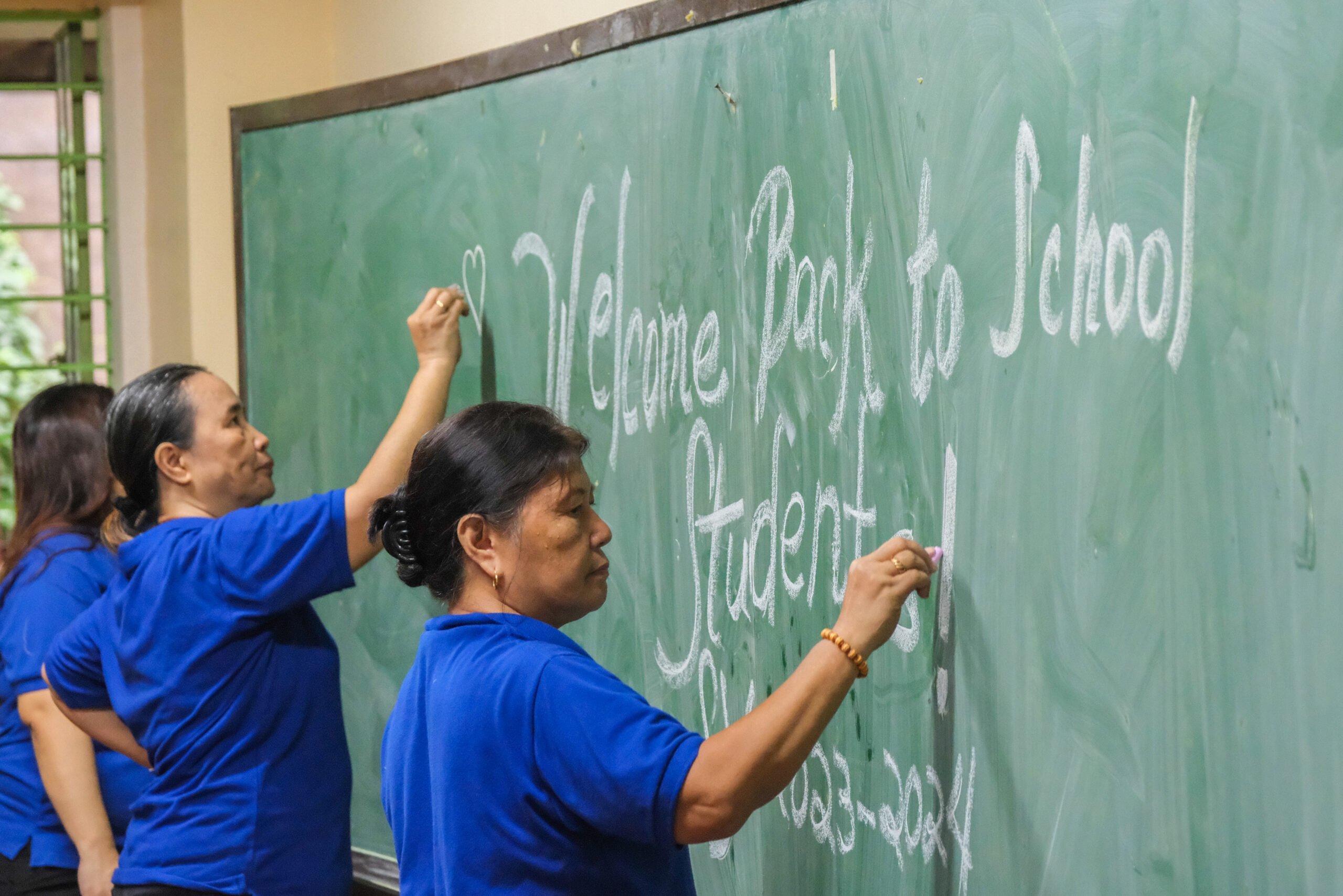 Teachers at Victorino Mapa High School write a welcome message for the incoming students on their blackboard while cleaning the school's grounds on 14 August 2023. | 📸 KING RODRIGUEZ.