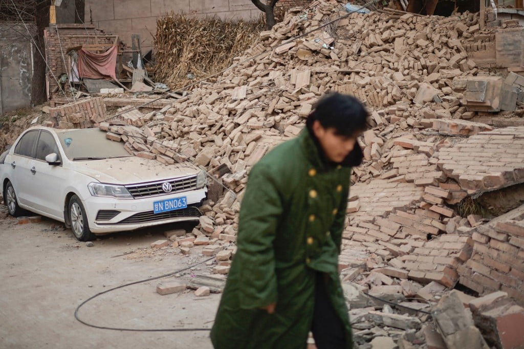 A man walks past a collapsed house in Dahejia in Jishishan County in northwest China's Gansu province on December 20, 2023. Survivors of China's deadliest earthquake in years huddled in aid tents on December 20 after overnight temperatures plunged well below zero, with the death toll rising to 131. (Photo by Pedro Pardo / AFP)