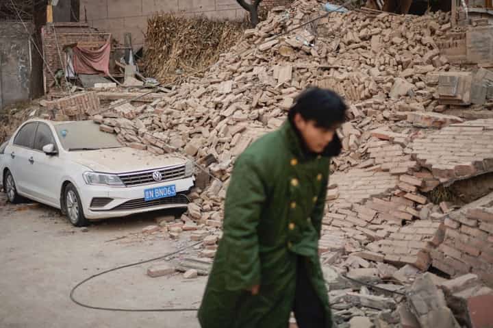 A man walks past a collapsed house in Dahejia in Jishishan County in northwest China's Gansu province on December 20, 2023. Survivors of China's deadliest earthquake in years huddled in aid tents on December 20 after overnight temperatures plunged well below zero, with the death toll rising to 131. (Photo by Pedro Pardo / AFP)