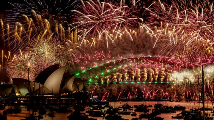 Fireworks explode over the Sydney Harbour Bridge and Sydney Opera House (L) during New Year's Eve celebrations in Sydney on January 1, 2024. (Photo by Izhar KHAN / AFP)