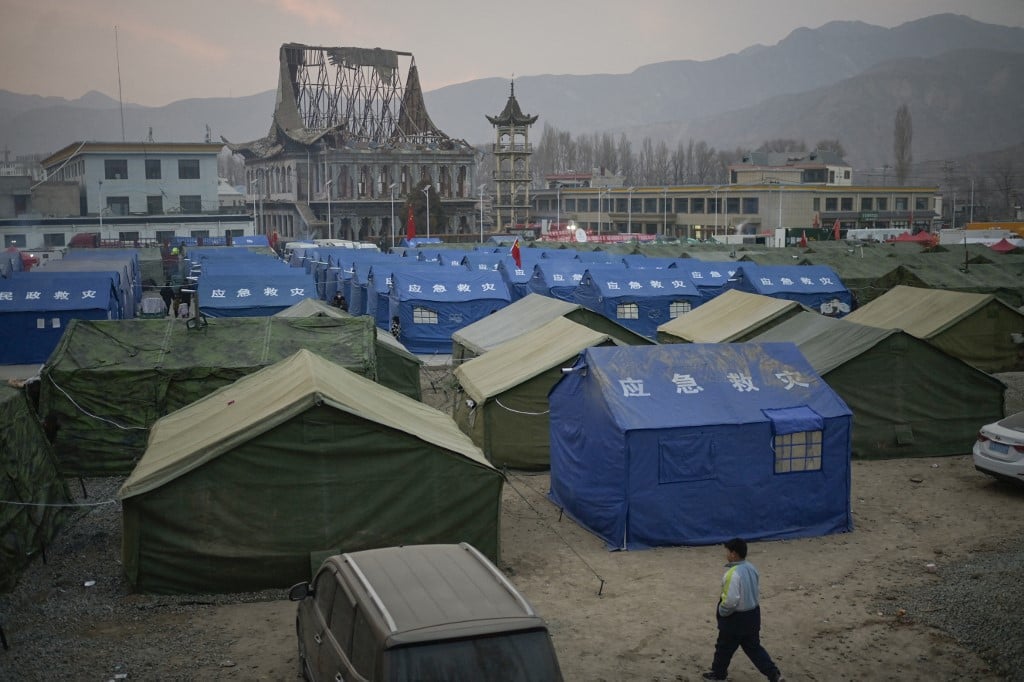 People are seen at a temporary shelter in the main square in Dahejia in Jishishan County in northwest China's Gansu province on December 20, 2023. Survivors of China's deadliest earthquake in years huddled in aid tents on 20 December after overnight temperatures plunged well below zero, with the death toll rising to 131. (Photo by Pedro Pardo / AFP)