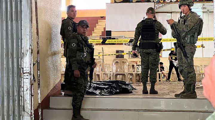 Military personnel stand guard at the entrance of a gymnasium while police investigators (background) look for evidence after a bomb attack at Mindanao State University in Marawi, Lanao del sur province on 3 December 2023. (Photo by Merlyn MANOS / AFP)