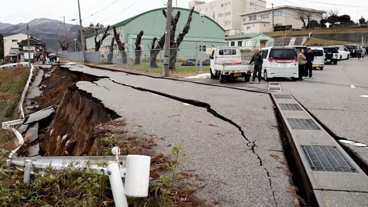 People stand next to large cracks in the pavement after evacuating into a street in the city of Wajima, Ishikawa prefecture on 1 January 2024, after a major 7.5 magnitude earthquake struck the Noto region in Ishikawa prefecture in the afternoon. (Photo by Yusuke FUKUHARA / Yomiuri Shimbun / AFP)