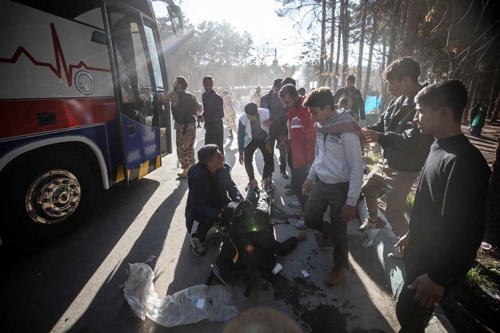 An injured man receives assistance after two explosions in quick succession struck a crowd marking the anniversary of the 2020 killing of Guards general Qasem Soleimani, near the Saheb al-Zaman Mosque in the southern Iranian city of Kerman on January 3, 2024. Photo by MEHR NEWS / AFP