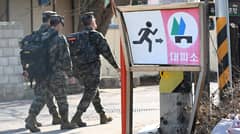South Korean marines walk past a shelter sign in a village on Yeonpyeong island, near the Northern Limit Line sea boundary with North Korea, on January 6, 2024. © Jung Yeon-Je, AFP