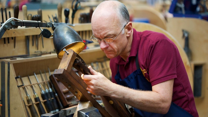 A master craftsman checks out the chequering on a gunstock. The better the chequering, the better the grip of a gun.