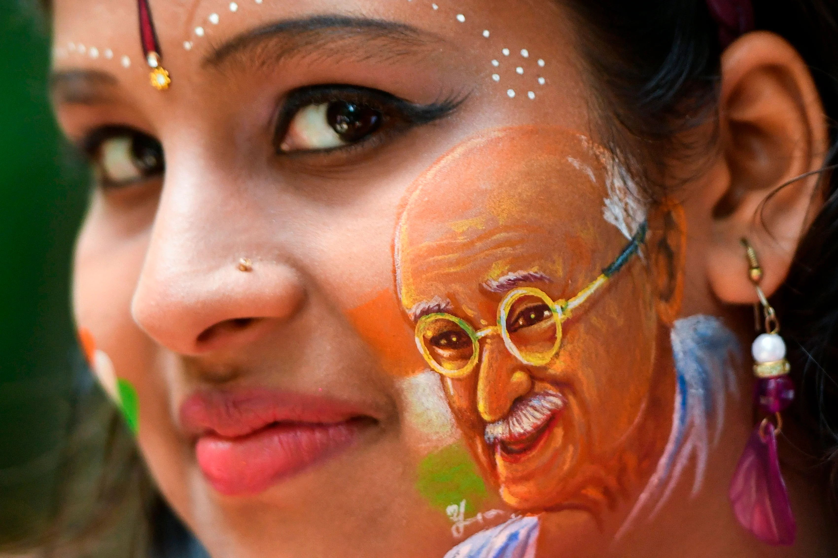 A girl poses for a picture with her face painted depicting a portrait of India's independence hero Mahatma Gandhi as the country celebrates its 73rd Independence Day, which marks the end of British colonial rule, in Bangalore