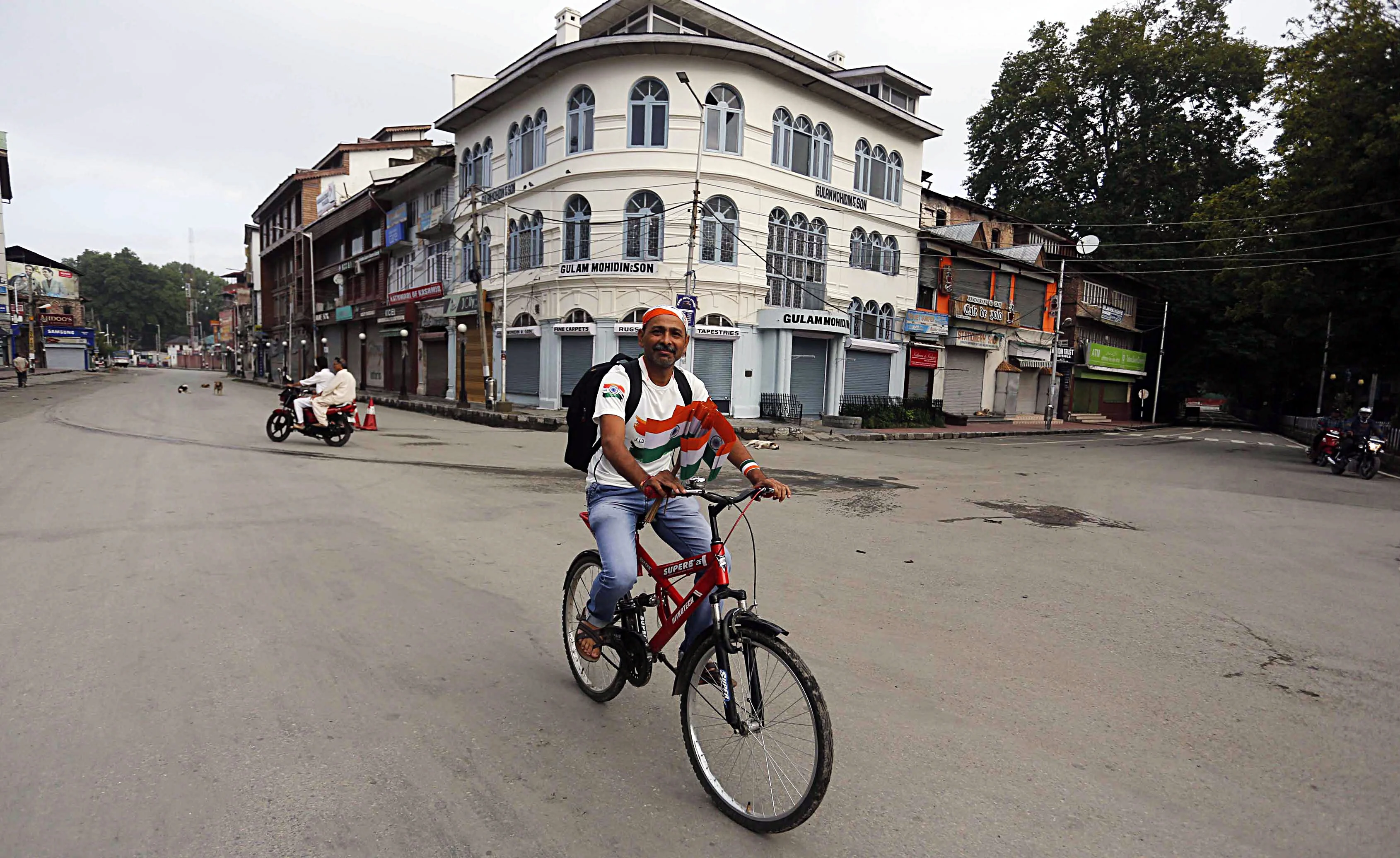 A man rides a bicycle with National flags during the 73rd Independence Day celebration in Srinagar