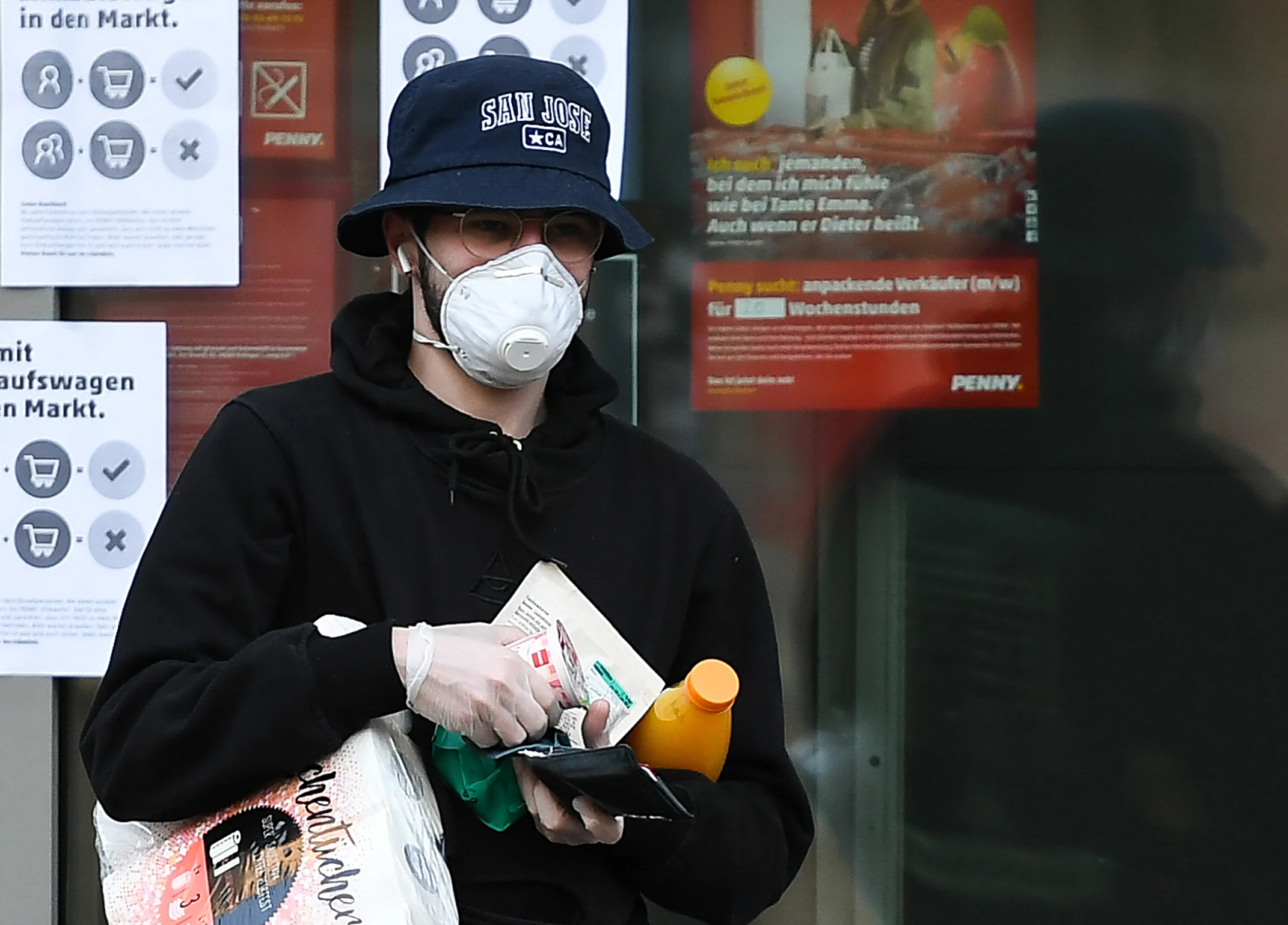 A man wearing a face mask and gloves leaves a supermarket in Frankfurt, Germany, March 25, 2020.
