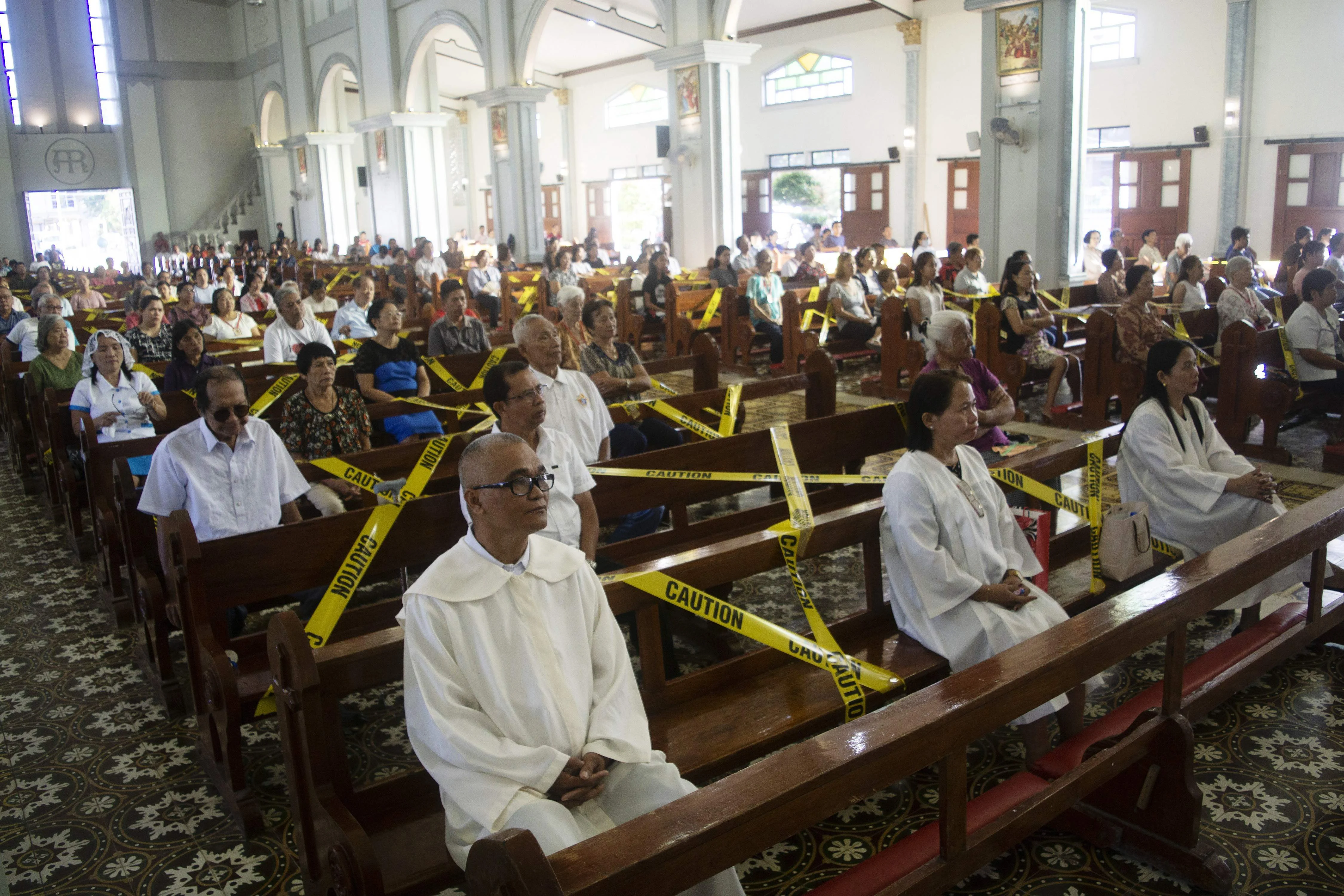 Catholic faithfuls sit on chairs with yellow line tapes, to separate church goers from sitting close to each other, as part of social distancing at a church in Borongan town, Eastern Samar province, central Philippines.