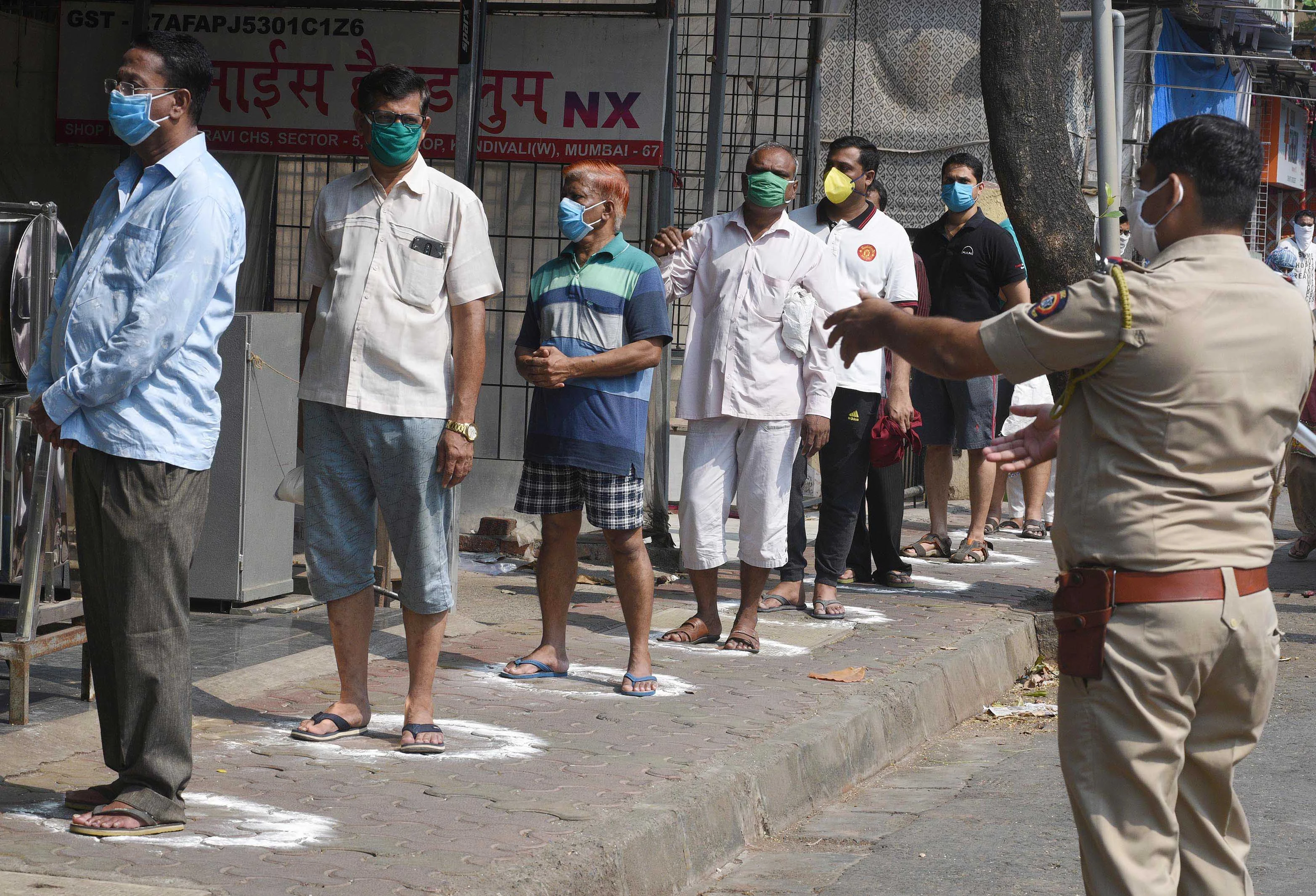 Police make sure people maintain safe distance in que while they purchase essential things.