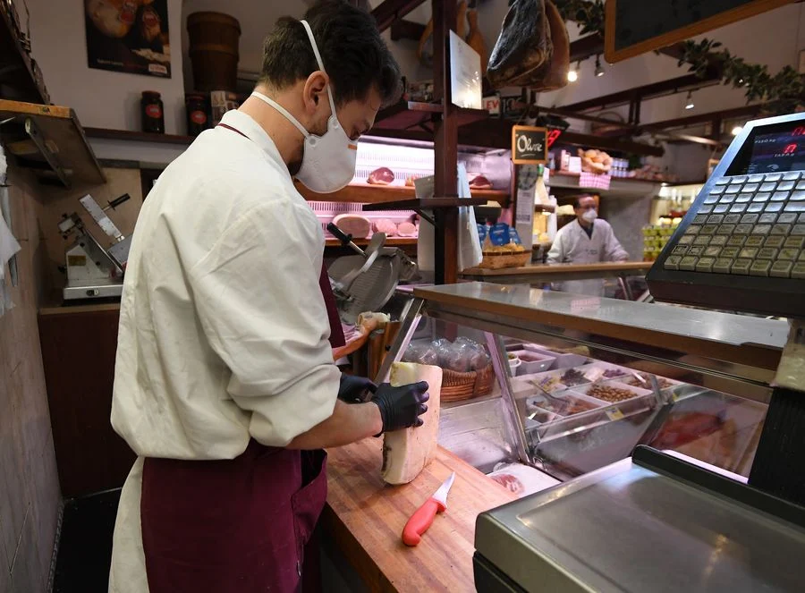 Staff members wearing face masks work in La Norcineria di Iacozzilli, a butcher shop in Rome, Italy, March 19, 2020.