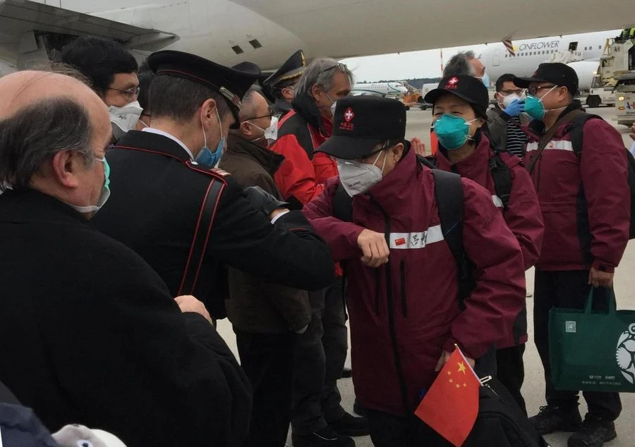 Local people greet members of the third Chinese medical team with an elbow bump instead of handshake as the medics arrive at Milan Malpensa Airport in Milan, Italy, March 25, 2020.