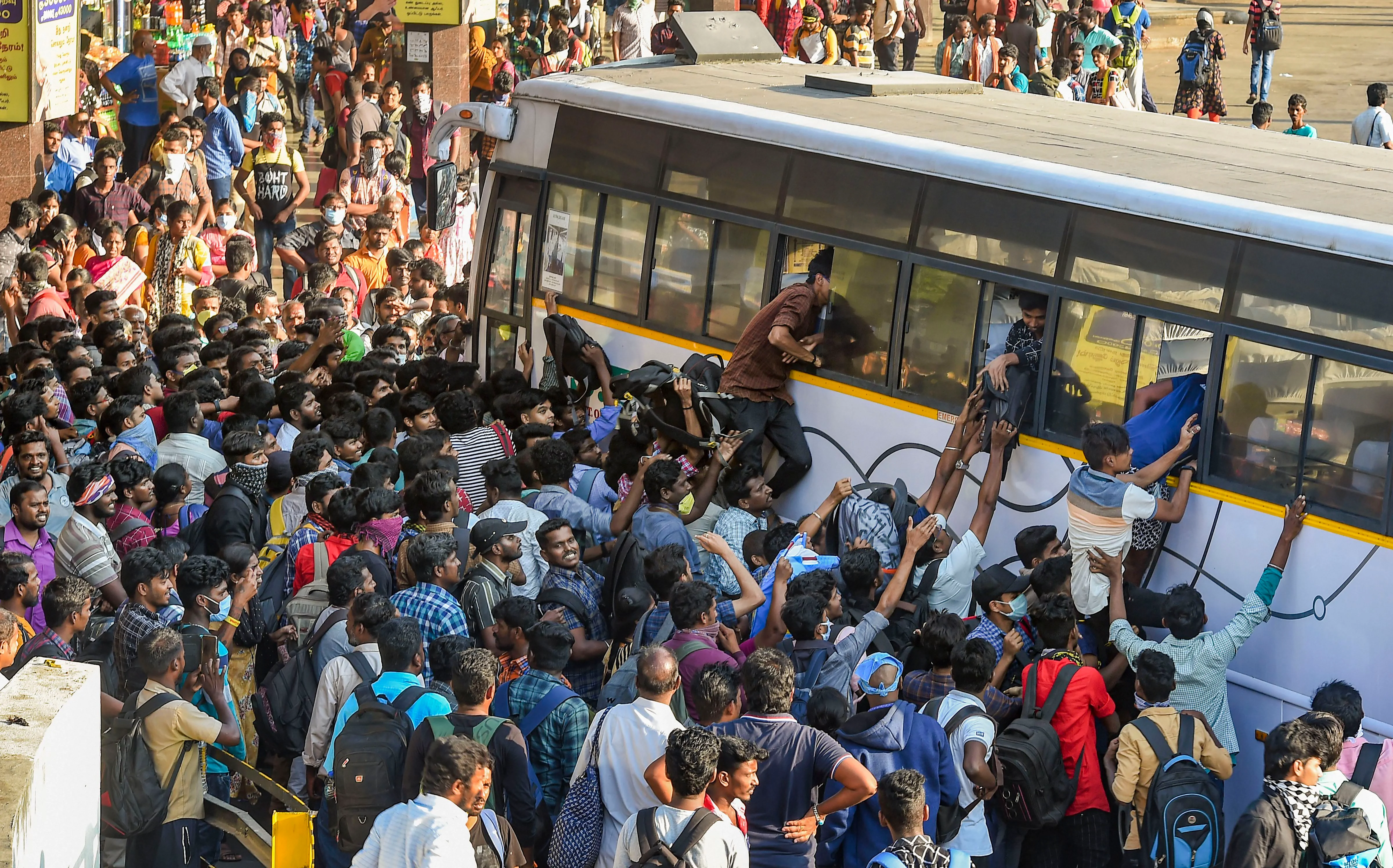 Passengers rush to board State Express Transport Corporation of Tamilnadu (SETC) bus after lockdown announcement in view of coronavirus pandemic, at Koyambedu bus terminal, in Chennai, Monday, March 23, 2020.