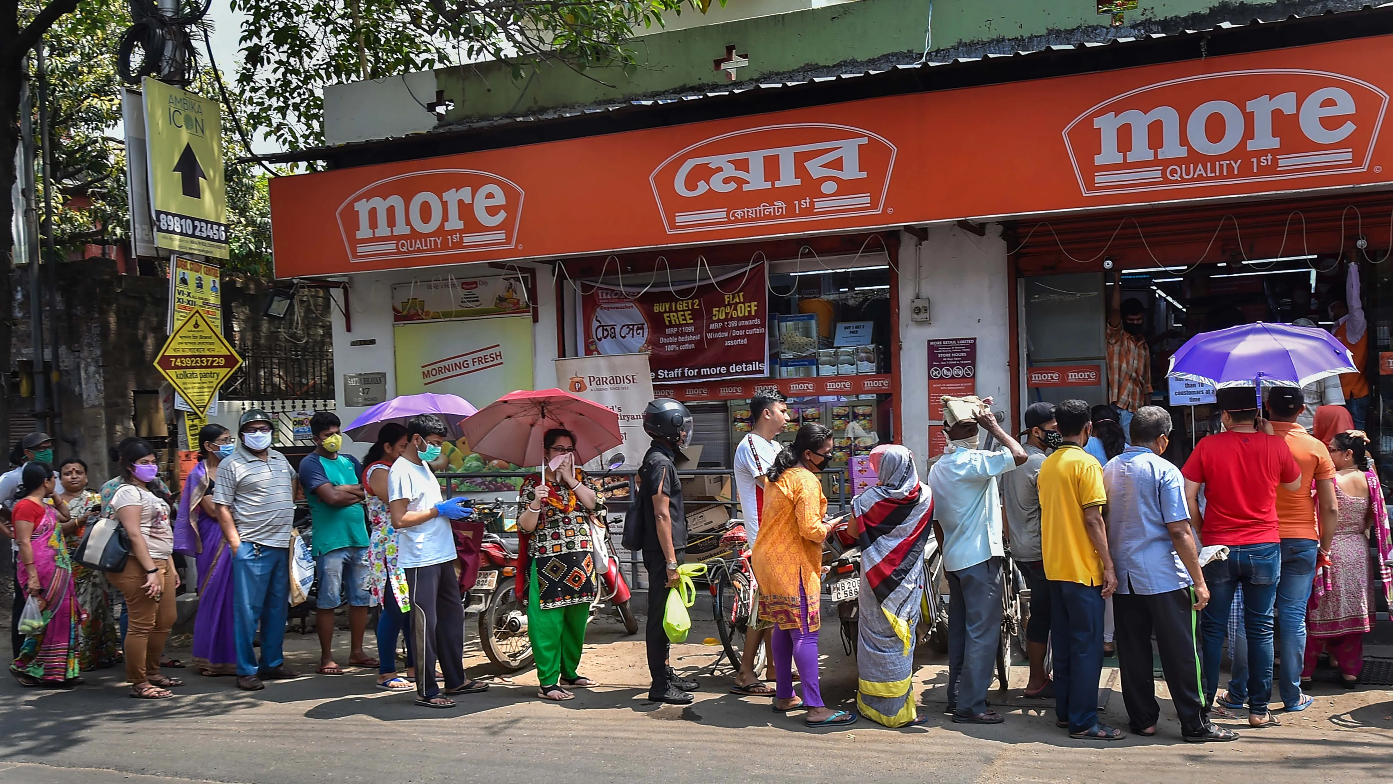 Locals stand in a queue to buy daily essentials before lock down amid rising concerns over the coronavirus pandemic, in Kolkata, Monday, March 23, 2020.