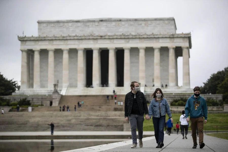 People wearing masks walk near the Lincoln Memorial in Washington D.C., the United States, on April 26, 2020.
