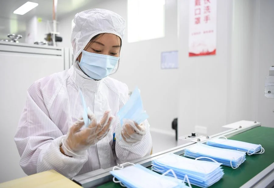 A staff member works on the face mask production line at the workshop of GAC Component Co., Ltd. in south China's Guangdong Province, Feb. 20, 2020.