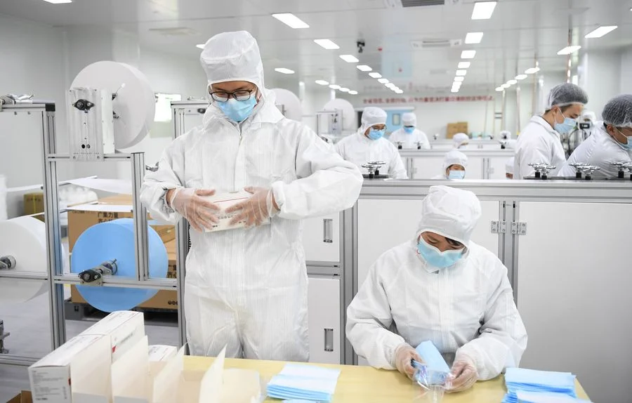Staff members work on the face mask production line at the workshop of GAC Component Co., Ltd. in south China's Guangdong Province, Feb. 20, 2020.