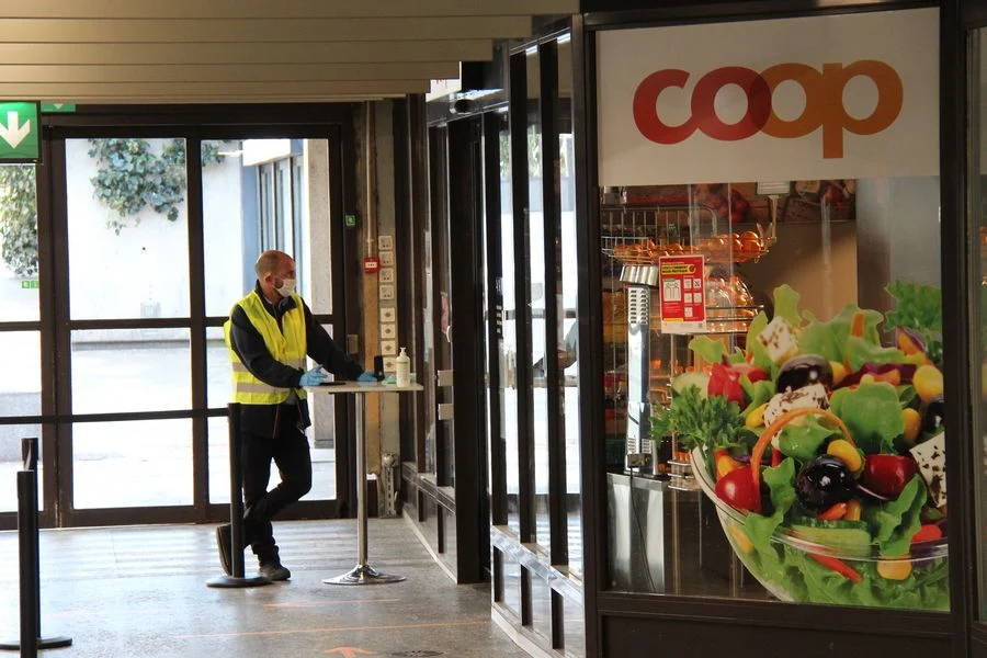 A man wearing a face mask works at the entrance of a supermarket in Geneva, Switzerland, on March 31, 2020.