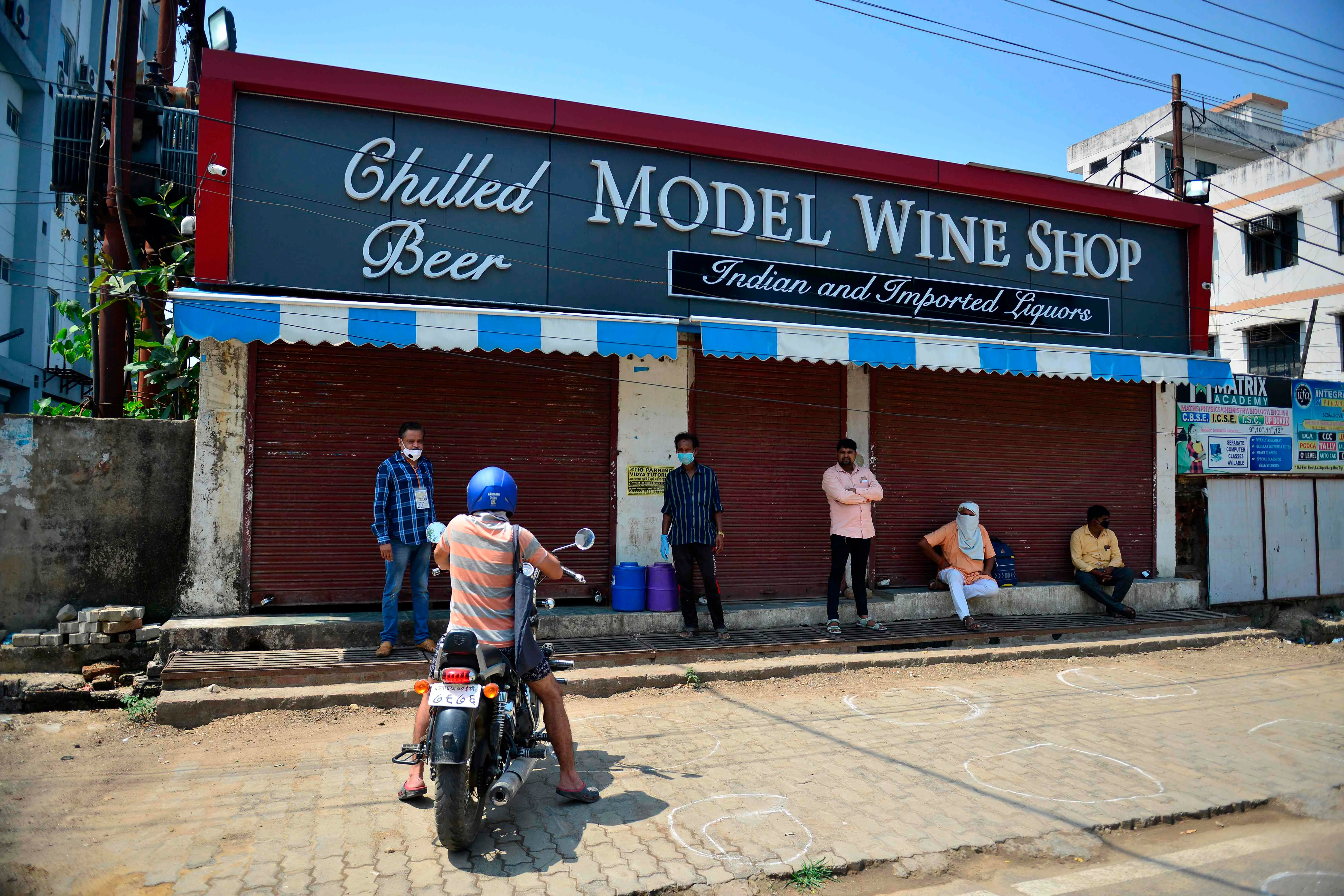 People stand as they wait to buy alcohol at a liquor shop after the government eased a nationwide lockdown as a preventive measure against the COVID-19 coronavirus, in Allahabad