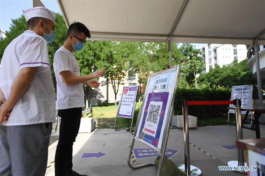 A student scans a QR code to register his health information in front of a canteen in Tsinghua University in Beijing, capital of China, June 6, 2020.