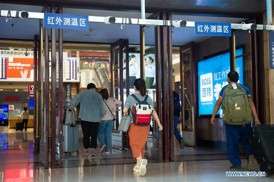 Passengers go through the body temperature monitoring area at the hall of Beijing Railway Station in Beijing, capital of China, June 18, 2020. Following the upgrade of emergency response to COVID-19 from Level III to Level II in Beijing, Beijing Railway Station has conducted strict measures to prevent and control the spread of the epidemic.