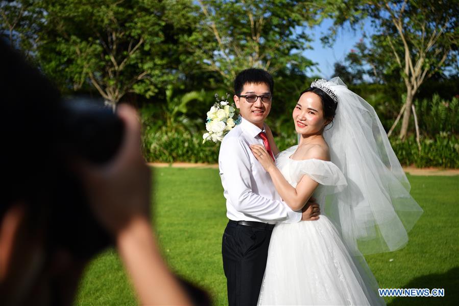 Ke Quan, a nurse from Renmin Hospital of Wuhan University, poses for a wedding photo with Yu Chen (R) at a resort in Sanya City, south China's Hainan Province, June 6, 2020. A group wedding ceremony was held here Saturday for newly-married couples from 15 provinces nationwide who once worked to fight against the COVID-19 outbreak.