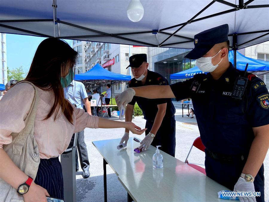 A staff member checks a student's body temperature at the gate of the Beijing Institute of Technology in Beijing, capital of China, June 6, 2020.