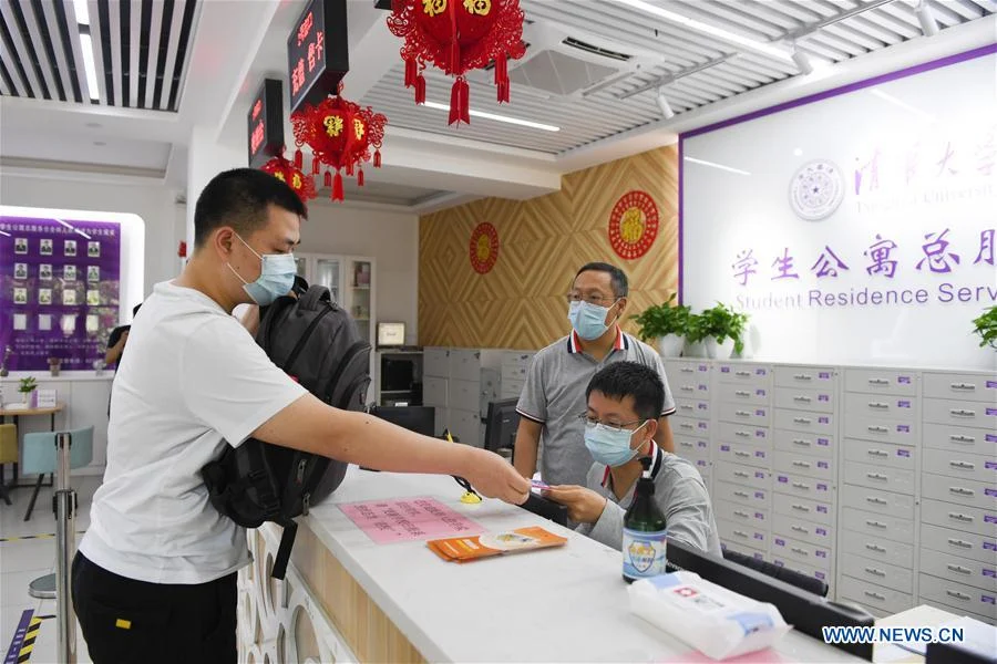 A student (1st, L) goes through procedures to move to his dormitory at Tsinghua University in Beijing, capital of China, June 6, 2020.