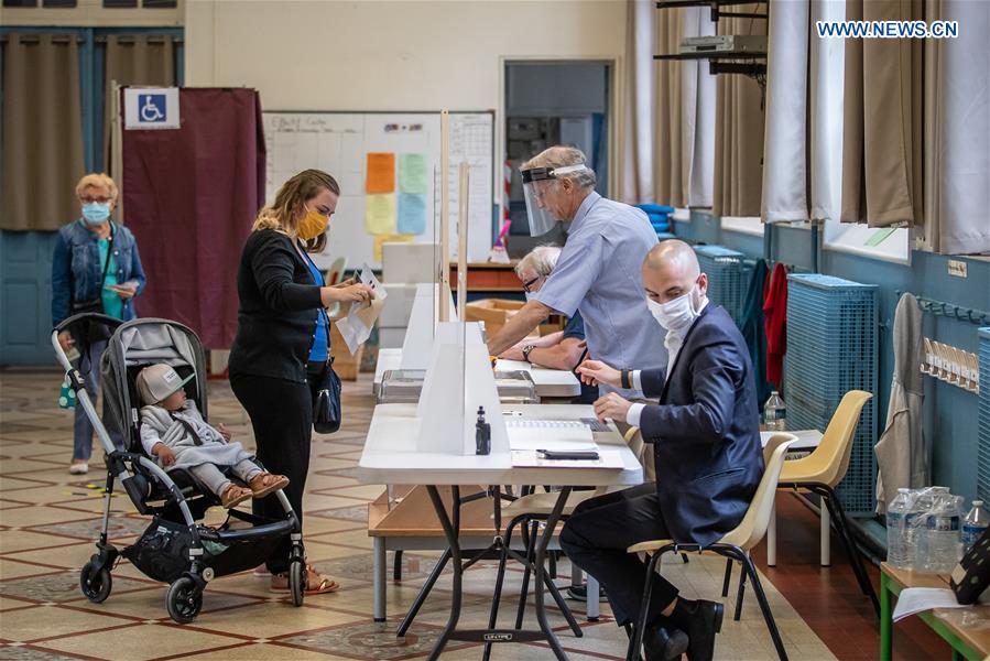 People wearing protective masks prepare to vote at a polling station during the second round of municipal elections in Paris, France, June 28, 2020.
