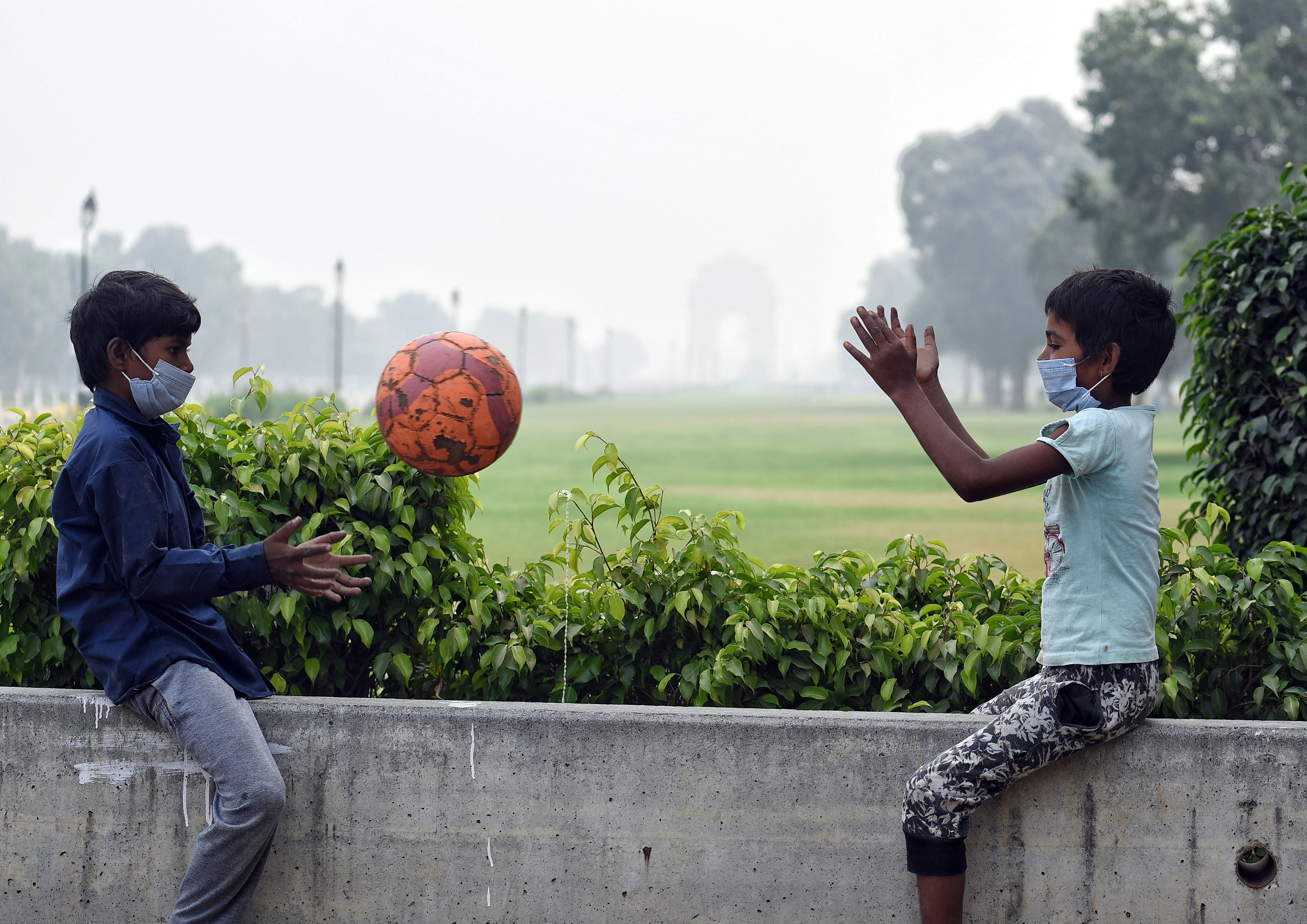 Two children play with a ball in a smoggy morning as the air quality deteriorates.