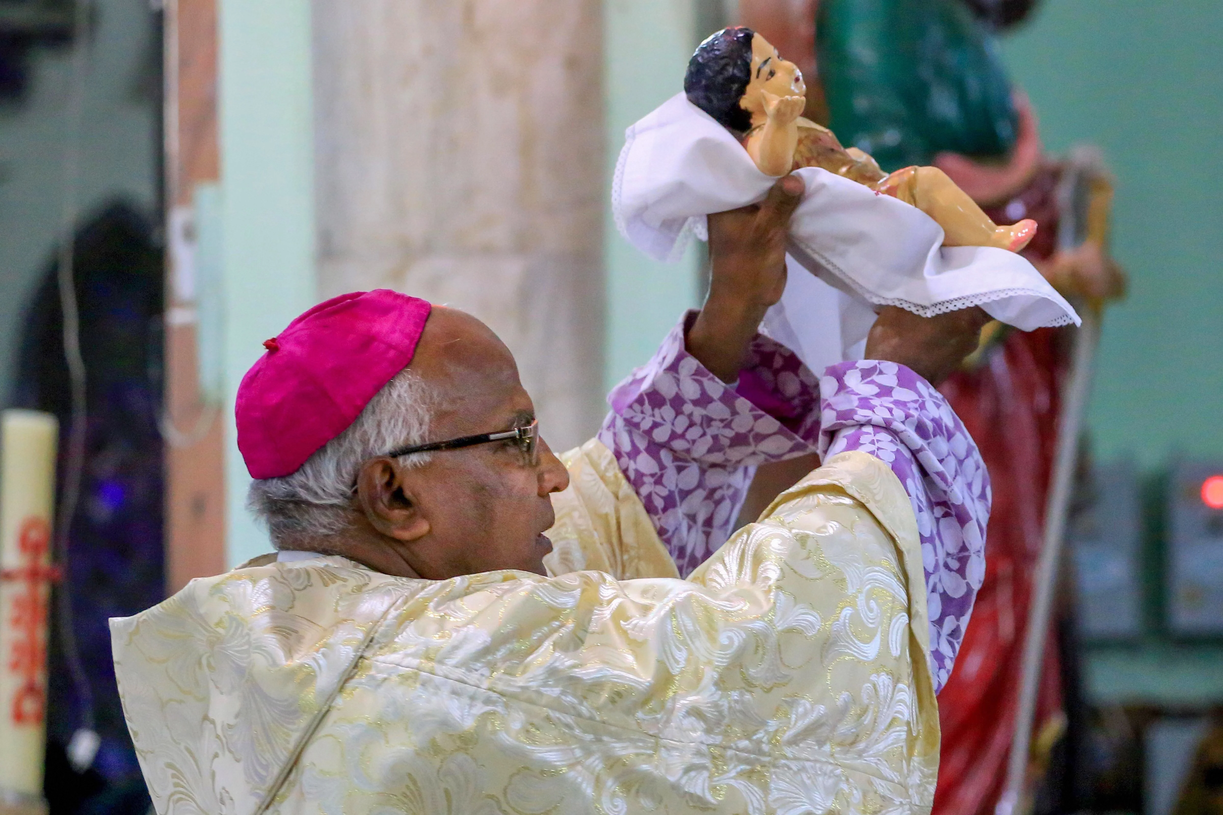 Archbishop holds a statue of baby Jesus during the Christmas celebrations at a church in Ajmer