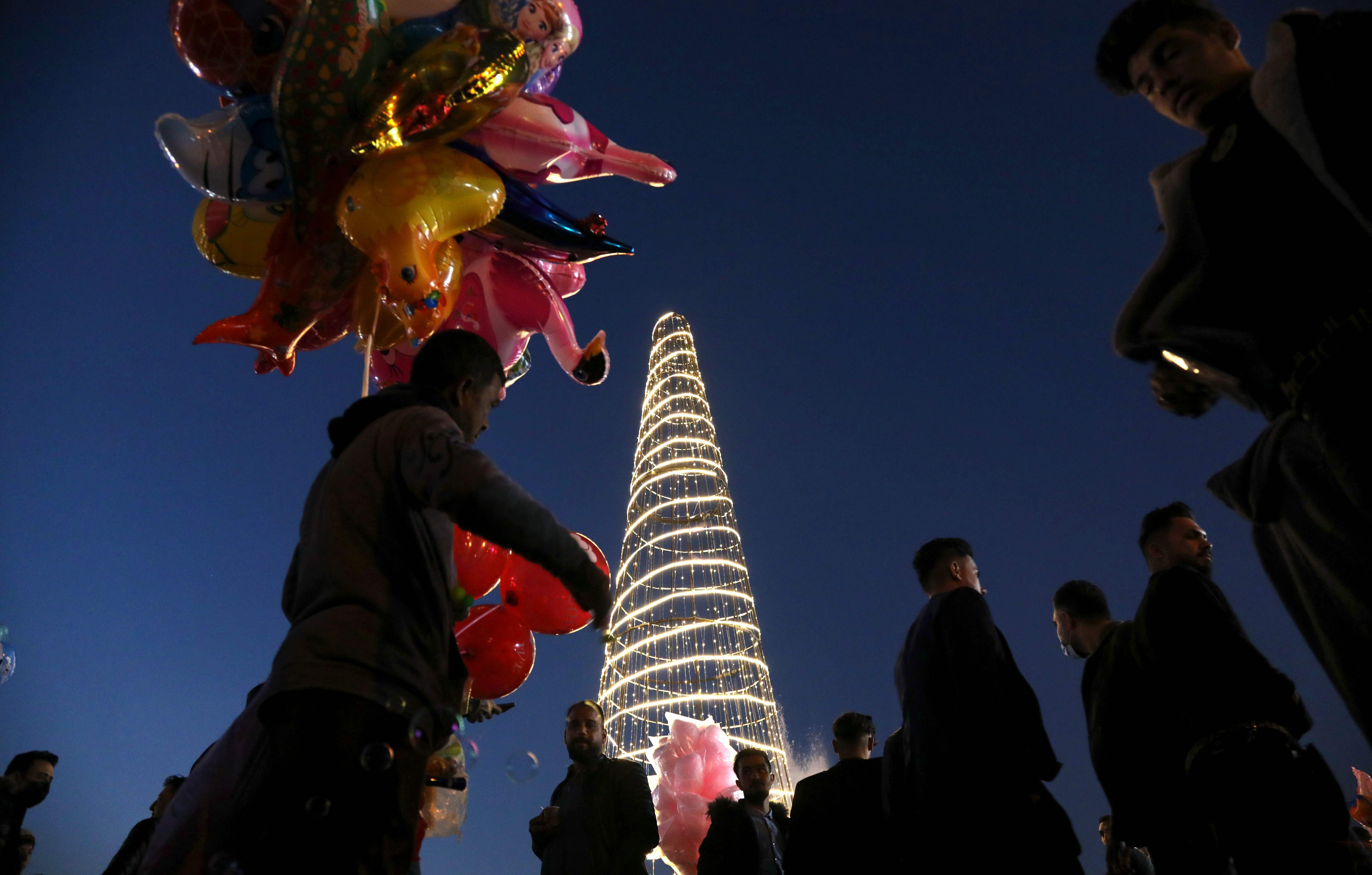 A man sells balloons as Iraqis gather around the citadel of Arbil, the capital of the autonomous Kurdish region of northern Iraq, to celebrate the new year on December 31, 2020.