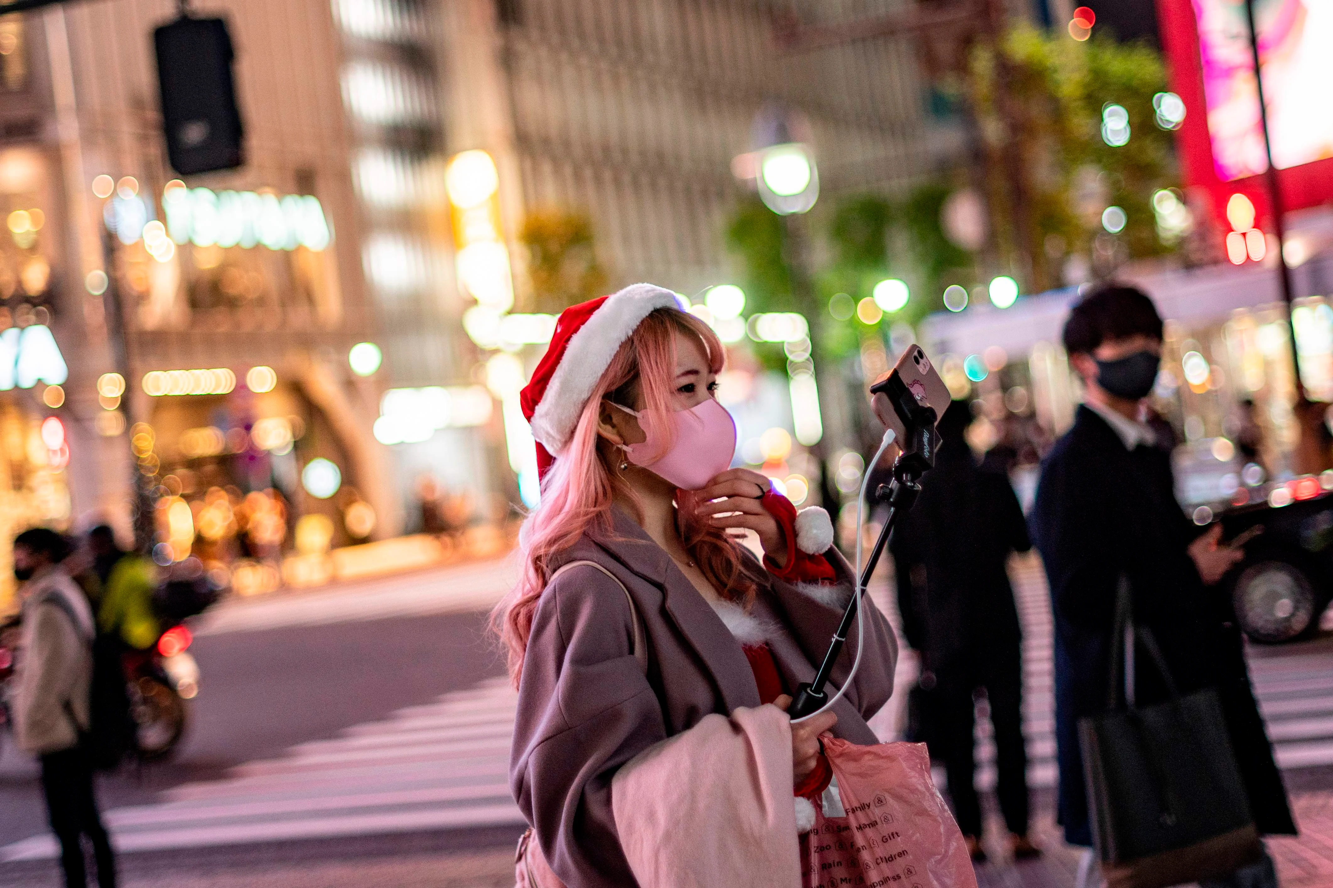 A woman wearing a Santa hat takes video clips on Christmas eve, in Shibuya district of Tokyo
