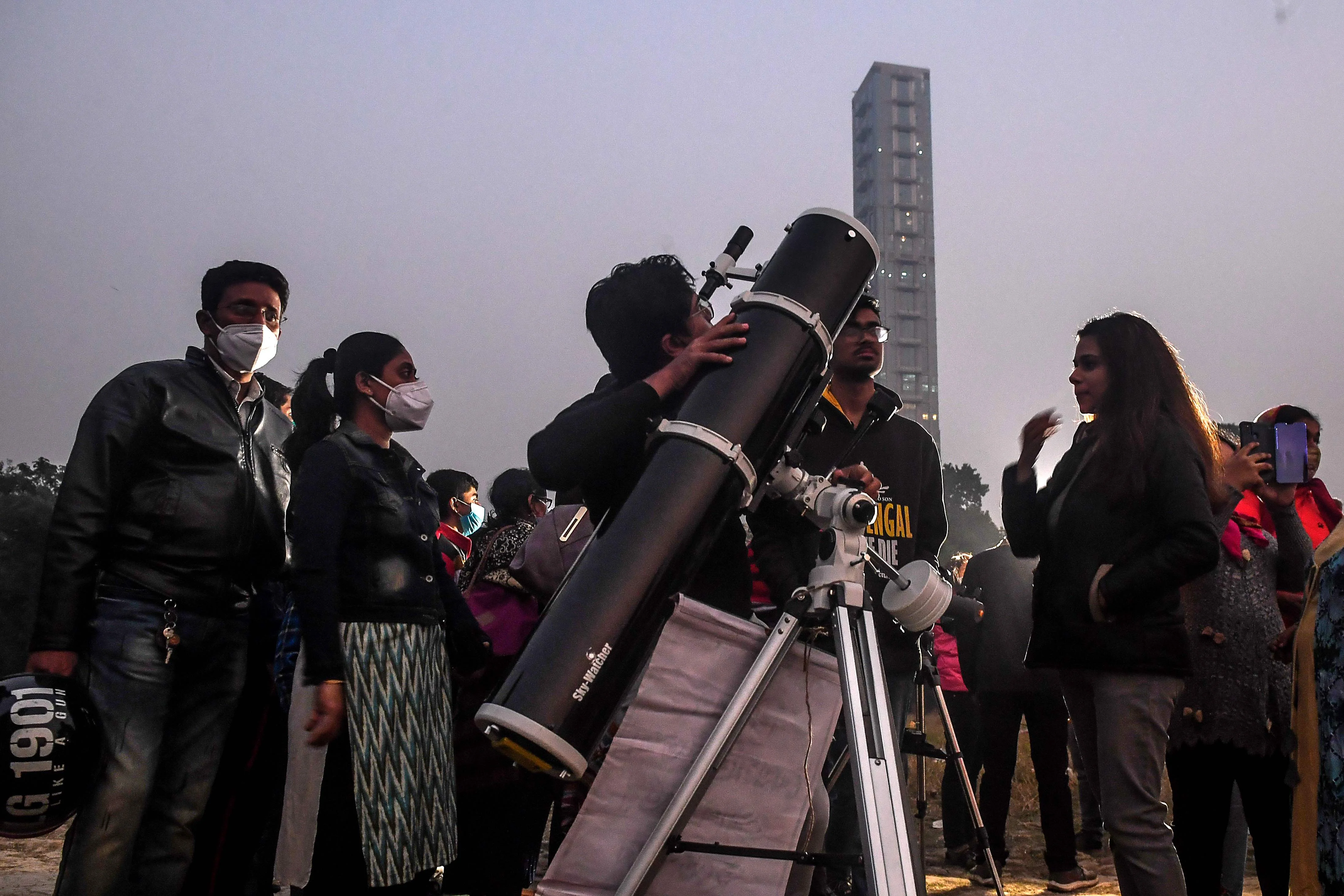 People stand in a queue to see a great conjunction of Jupiter and Saturn at the Maidan area in Kolkata on December 21, 2020.