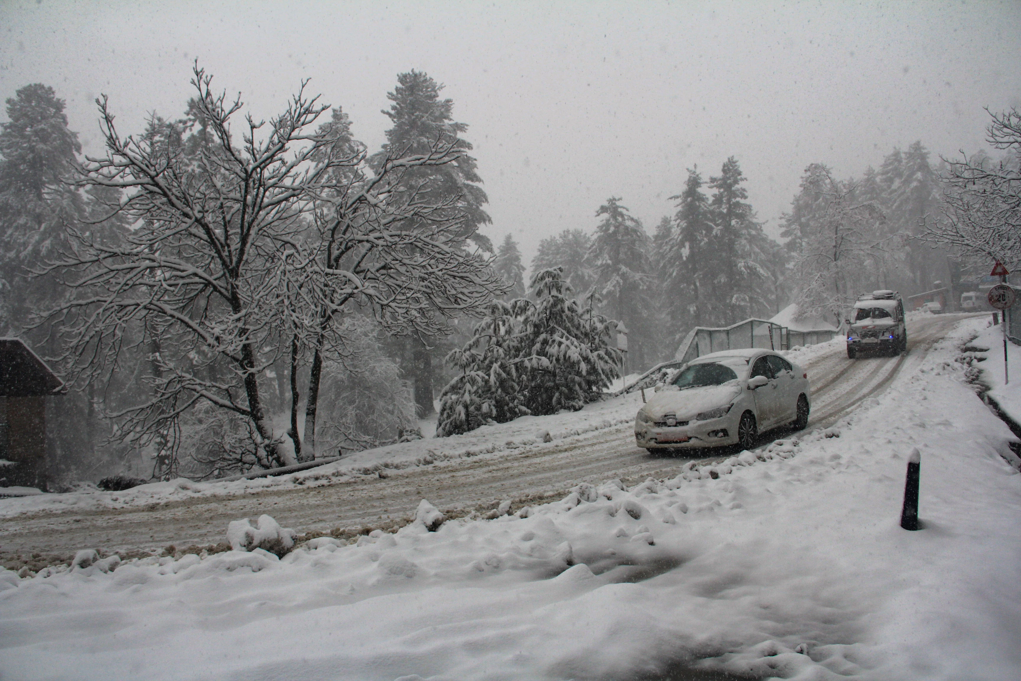 Vehicles move through a snow-covered road during a snowfall in parts of Kashmir on Saturday