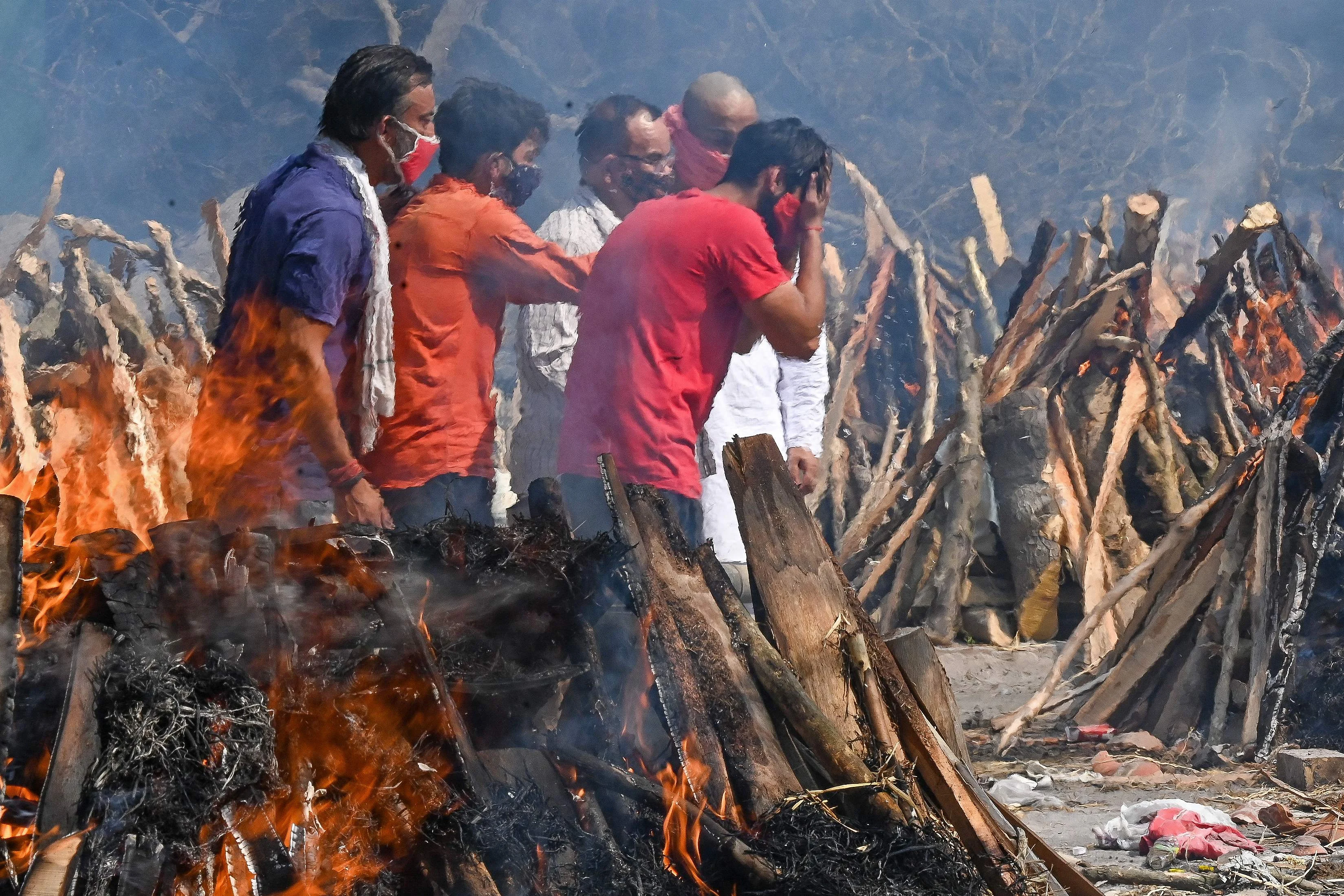 A man reacts as he performs the last rites of his relative amid the funeral pyres of victims who died of the Covid-19 coronavirus during mass cremation held at a crematorium in New Delhi on April 27, 2021.