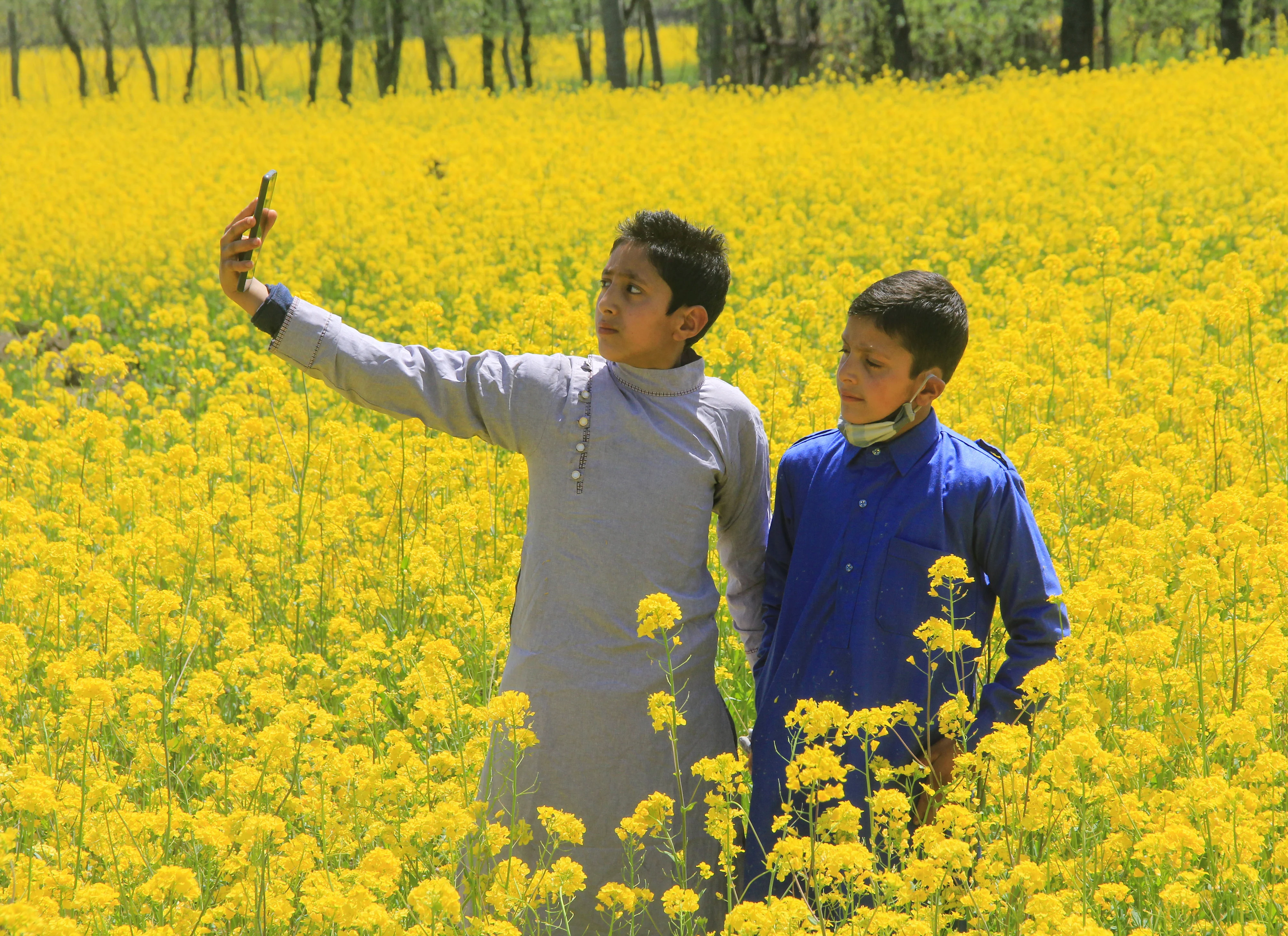Children take selfies in a blossoming mustard field on the outskirts of Srinagar, Kashmir.