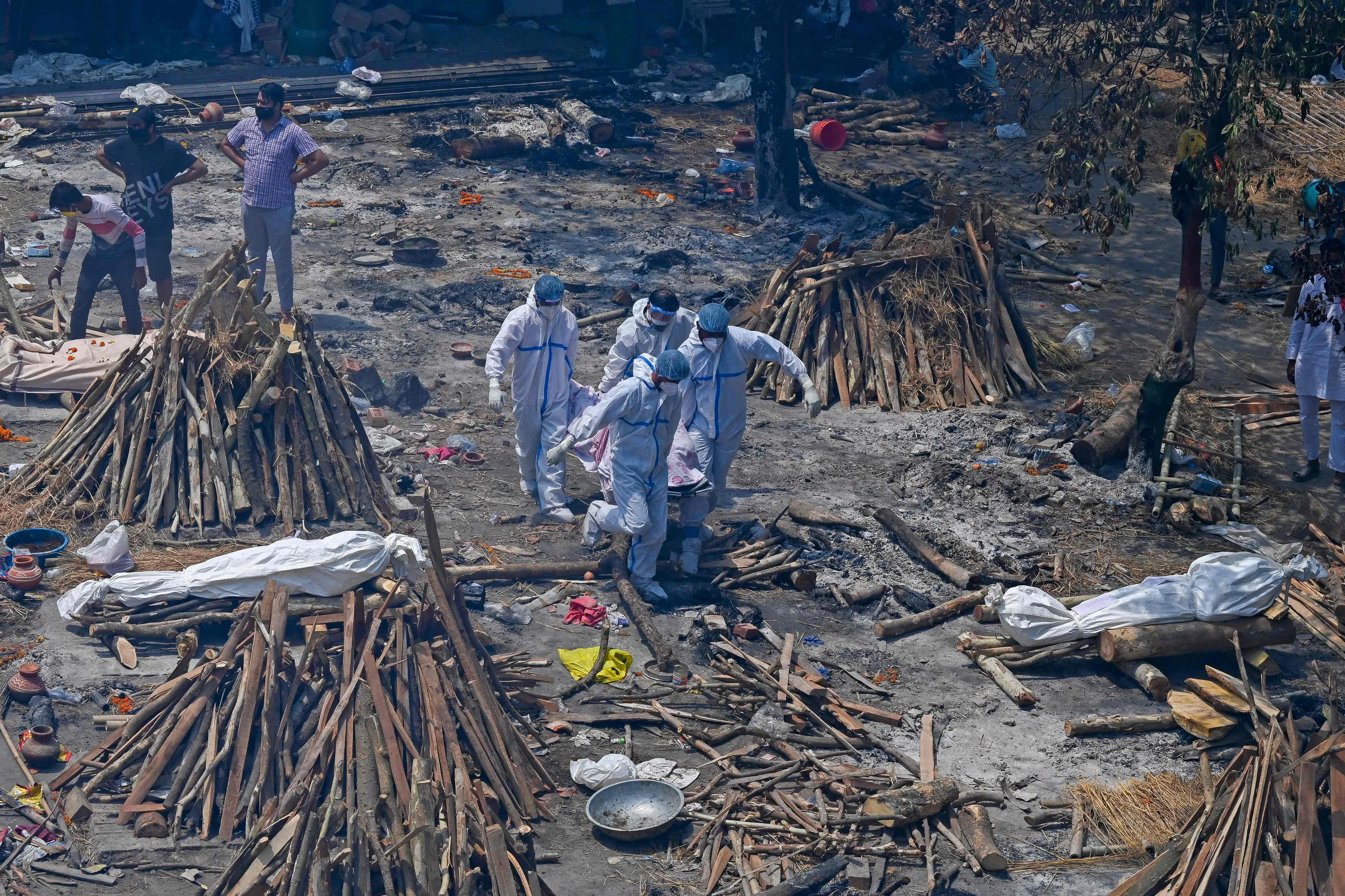 Family members and relatives perform the last rites amid the funeral pyres of victims who died of the Covid-19 coronavirus during mass cremation held at a crematorium in New Delhi on April 27, 2021.