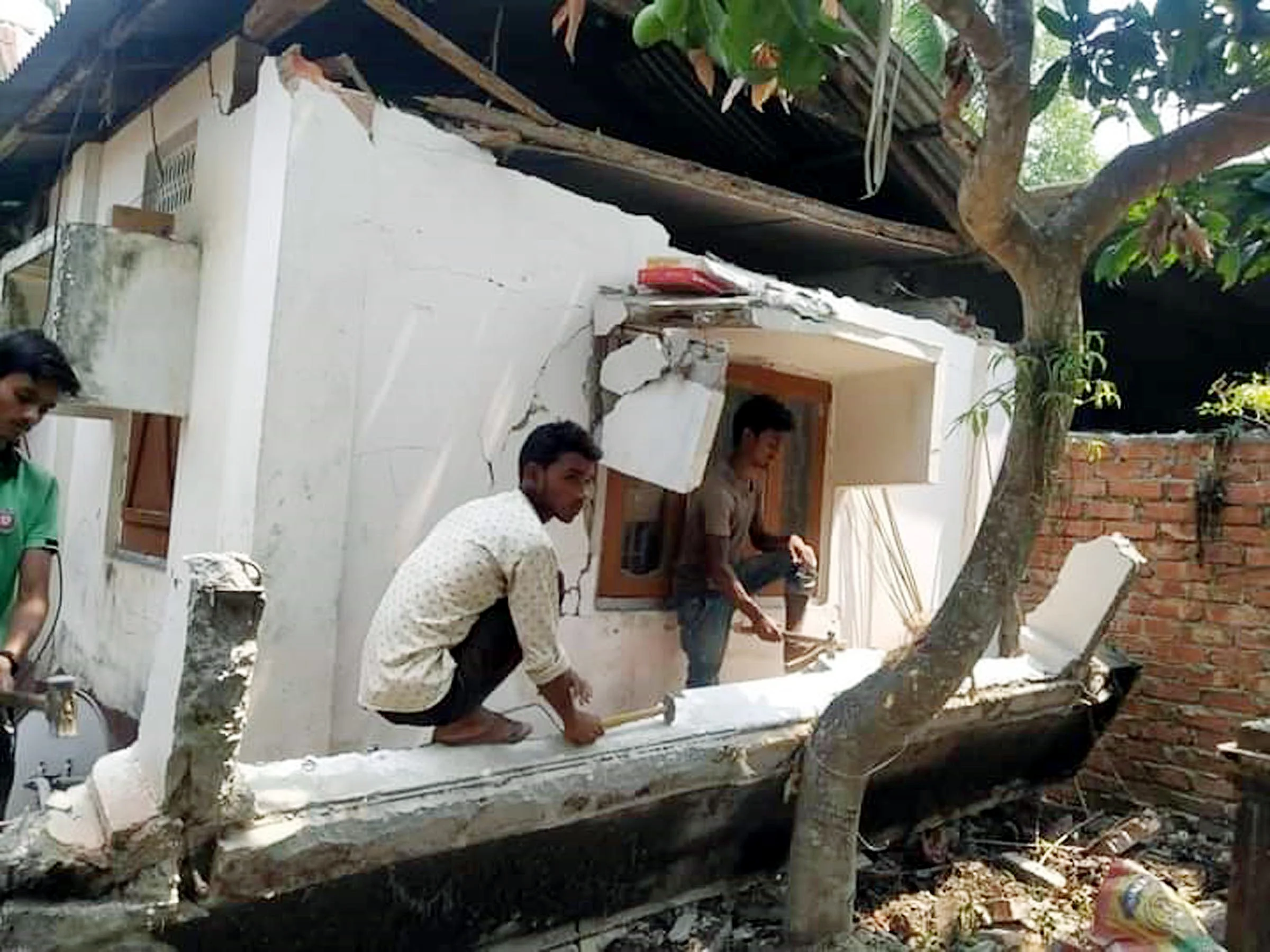 People look at the damaged house after the earthquake, at Darrang district on Wednesday.